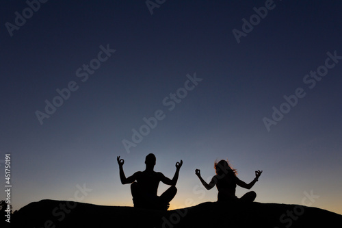 Young couple practicing yoga at sunset. Backlight. Copy space.