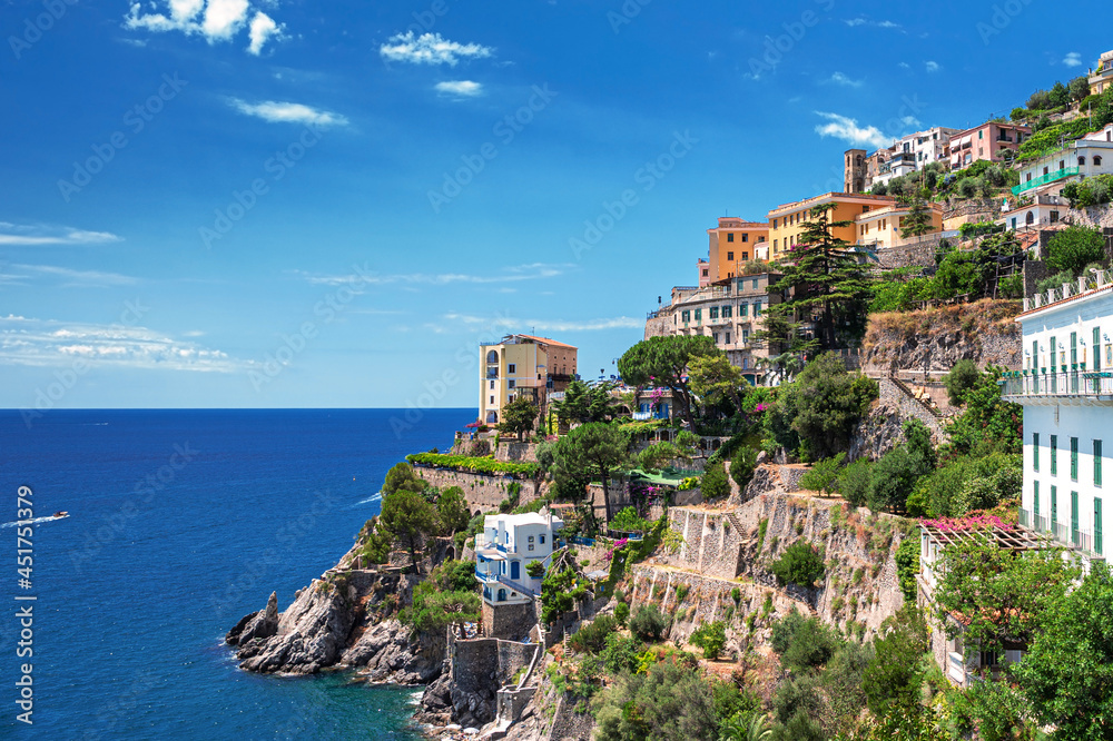 Panoramic view of a typical scene on the Amalfi Coast in Italy, where colorful houses are stacked on the rocks jutting into the deep blue sea. 