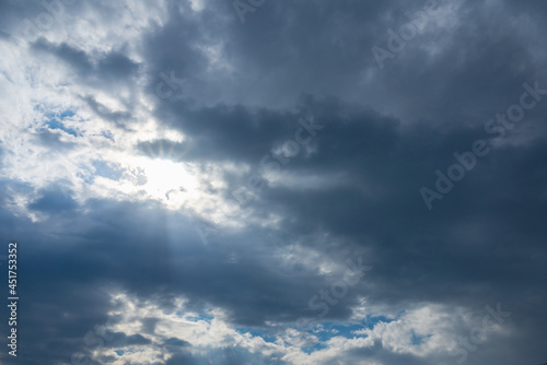 Dramatic blue sky with clouds and sun rays.Summer Sun rays at sunset.