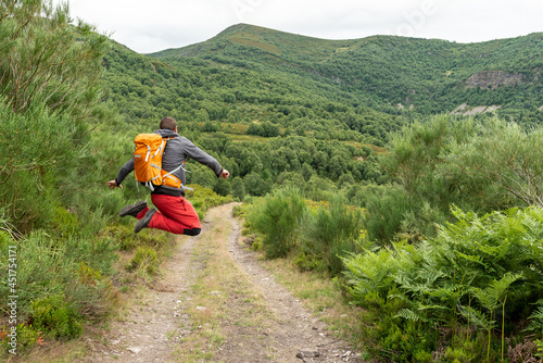 Man jumping while is trekking solo at the mountains. Summer active vacations. Freedom concept.  photo