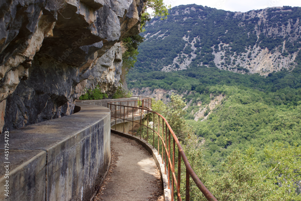 Fototapeta premium Chemin à Gourdon qui suite l'aqueduc en bordure du précipice. Le sentier est étroit et assez ancien avec des passages vertigineux