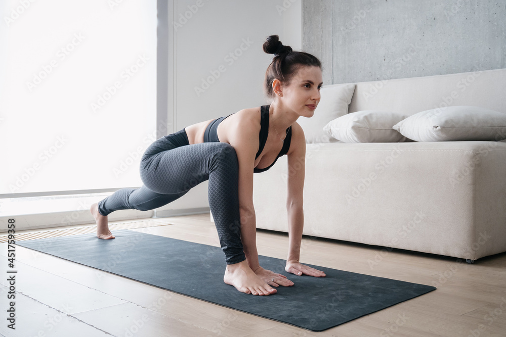 Woman performing lizard asana on mat at home Woman performing lizard asana on mat at home