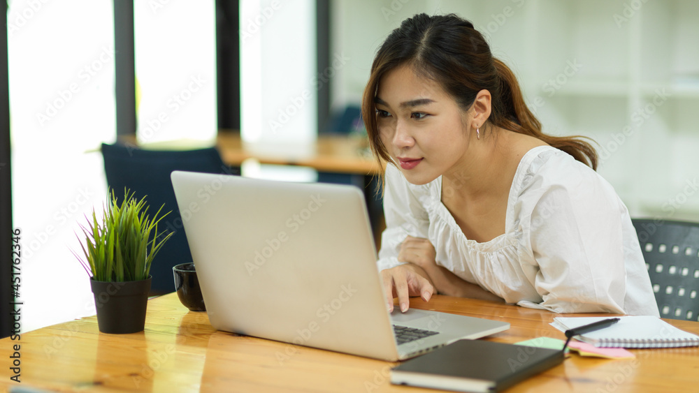 Focused beautiful asian woman using laptop, look at laptop screen, reading email Focused beautiful asian woman using laptop, look at laptop screen, reading email