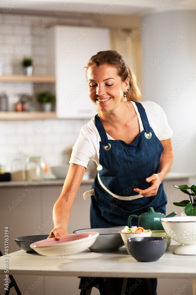 Young woman setting a table for lunch. Smiling happy woman preparing a delicious food.