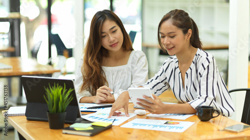 two casual asian businesswomen discussing work in office