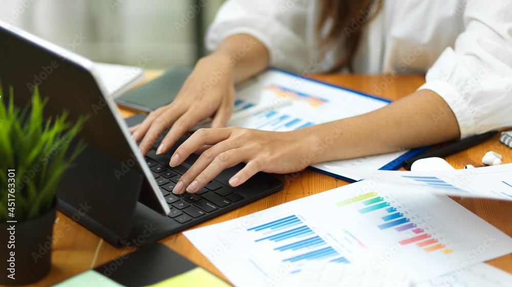 Closeup businesswoman hands , working with smart tablet and financial documents
