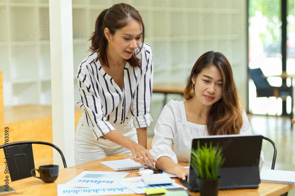Happy two female entrepreneur reading business contract deal on tablet together Happy two female entrepreneur reading business contract deal on tablet together
