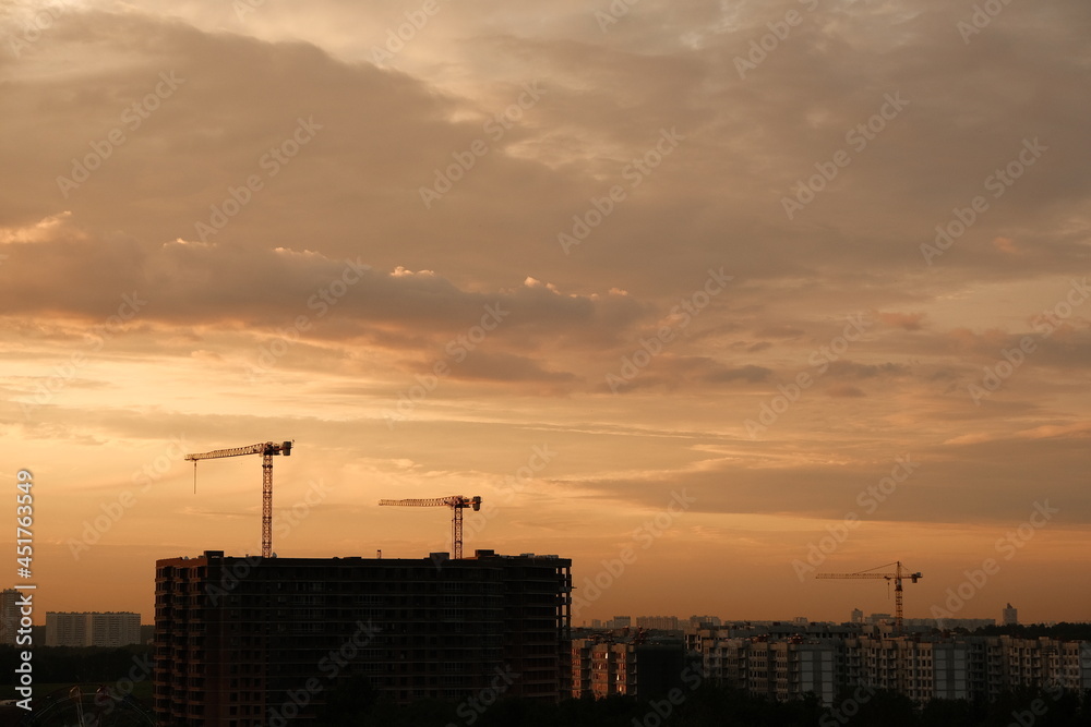 Construction cranes under the beautiful sunset sky