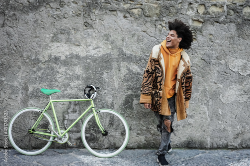 Young african boy having fun with his bicycle outdoor in the city - Fashion style photo - Focus on face