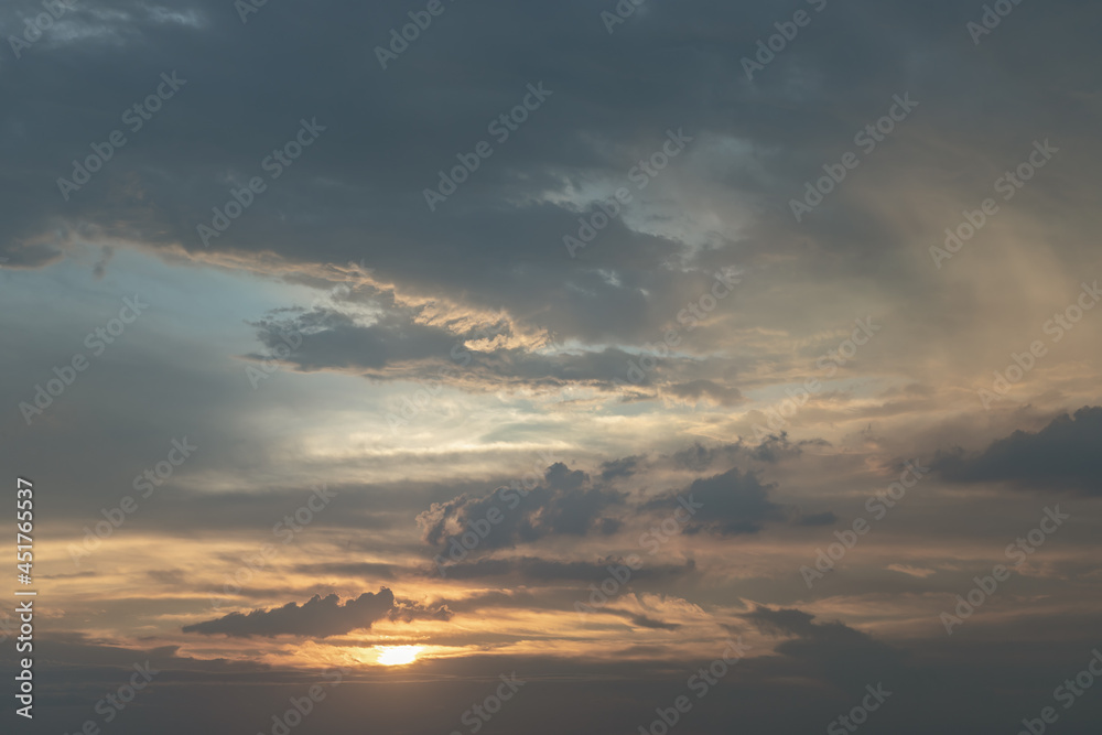 The sun shines through the clouds in the sunset sky with dramatic light. The shape of the clouds evokes imagination and creativity. They can be used as wallpapers that look amazing. Copy space.