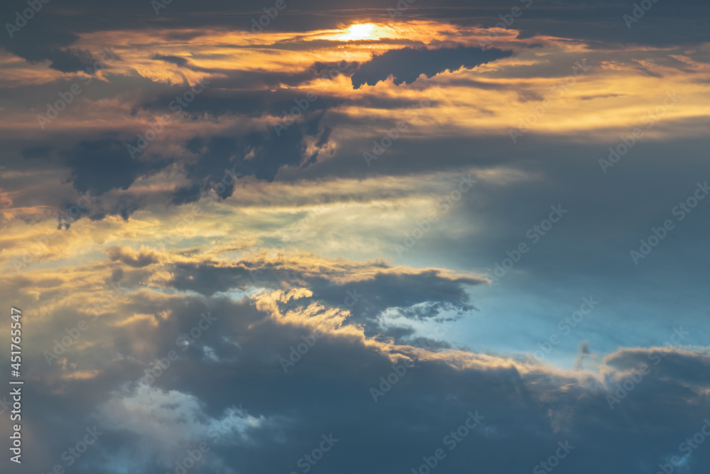 The sun shines through the clouds in the sunset sky with dramatic light. The shape of the clouds evokes imagination and creativity. They can be used as wallpapers that look amazing. Copy space.