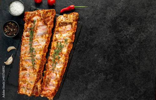 Canvas Print raw pork ribs marinated with spices on a stone background with copy space for yo