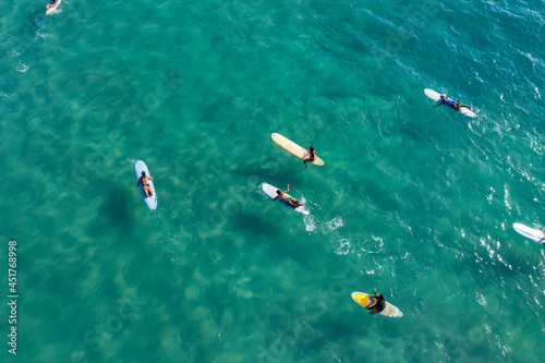 Surfers sit on their boards waiting for the waves in the blue sea, clear water.