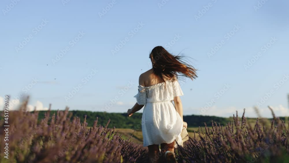 Happy young woman in a white dress running through lavender field. Behind beautiful girl in Provence, France. Aromatherapy Happy young woman in a white dress running through lavender field. Behind beautiful girl in Provence, France. Aromatherapy