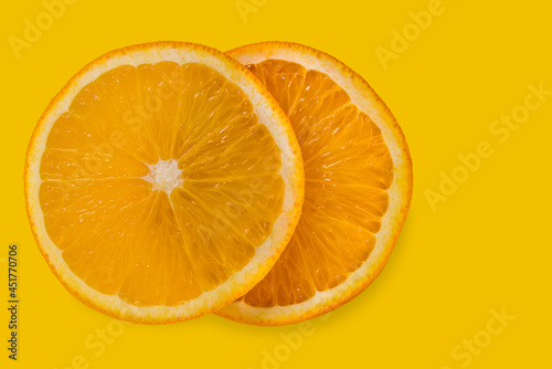 Two slices of orange isolated on yellow background with copy space