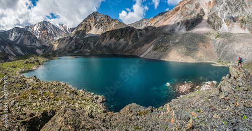 Panoramic view to mountain lake on background of mountains. Atmospheric green landscape with lake in high mountain valley. Great scenery with mountain lake in highland glen