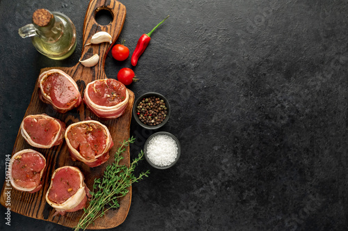 raw pork tenderloin medallions wrapped in bacon on a stone background 	with copy space for your text	 
