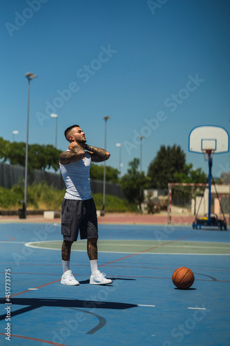 Chico joven atletico tatuado jugando a baloncesto en cancha azul © MiguelAngelJunquera