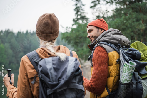 young man with backpack looking at woman in forest