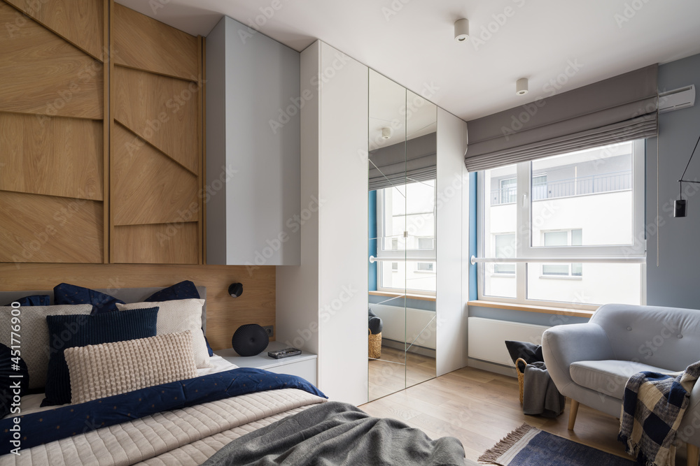 Fototapeta premium Spacious bedroom with window, wardrobe and armchair