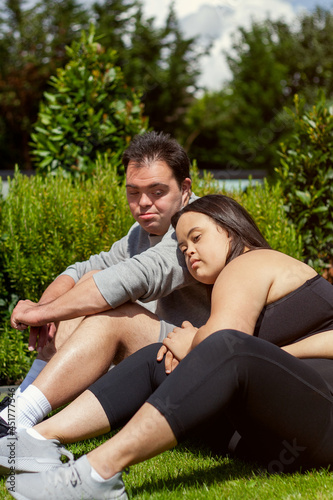 Young biracial couple with Down Syndrome in active wear resting head on each other © Anna Neubauer