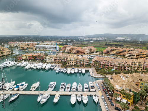 Unique aerial view of exclusive Sotogrande Bay - Costa del Sol. Cloudy day and rainy , beautiful sky colours. Luxury real estate and yacht. Famous location.  photo