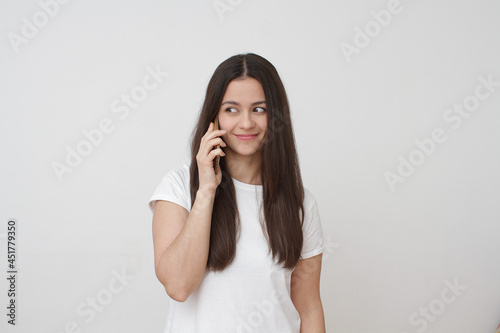 Inside portrait of young girl on white background. Young girl talking on phone. 