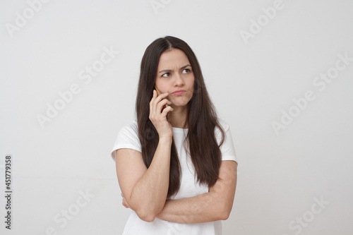 Upset young girl with phone on white background. Inside portrait of young girl.