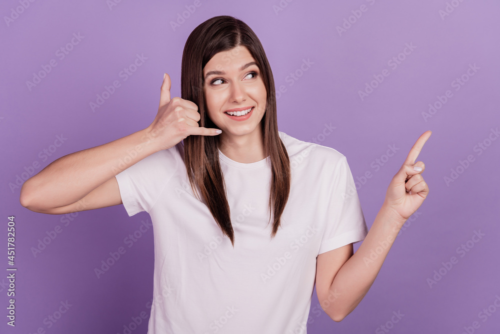 Funny young woman isolated on violet background point empty space make call phone fingers sign Funny young woman isolated on violet background point empty space make call phone fingers sign