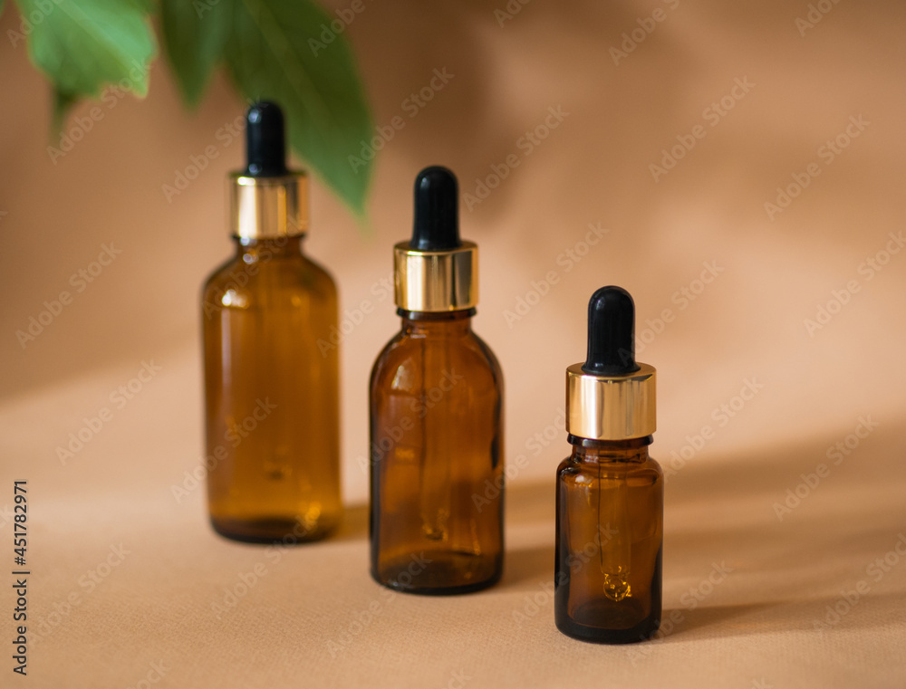 Three cosmetic bottles with a pipette on a beige background Three cosmetic bottles with a pipette on a beige background