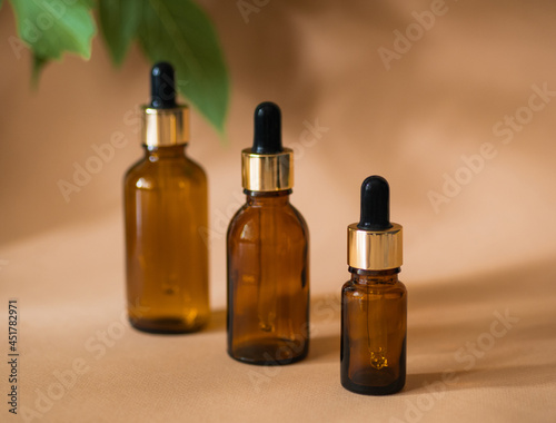 Three cosmetic bottles with a pipette on a beige background