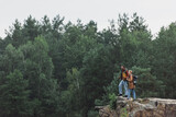 couple with hiking sticks standing on rocky cliff