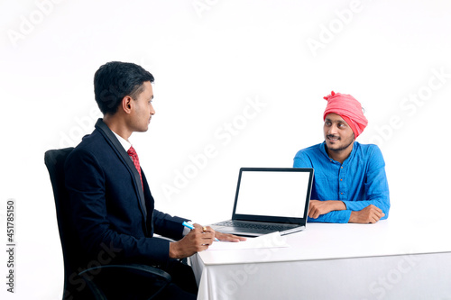 Young indian banker giving some information to farmer at office.