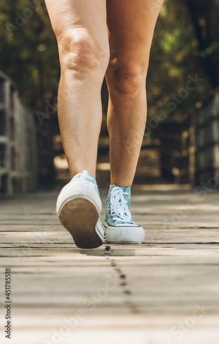 Legs of a woman walking across a wooden bridge