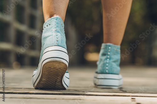 Ornate denim shoes of a woman walking outdoors