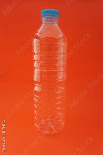 Close up Empty used plastic bottle isolated on an orange background and has a blue cap. For websites, knowledge, news, Recycling, plastic industry