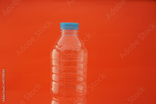 Close up Empty used plastic bottle isolated on an orange background and has a blue cap. For websites, knowledge, news, Recycling, plastic industry