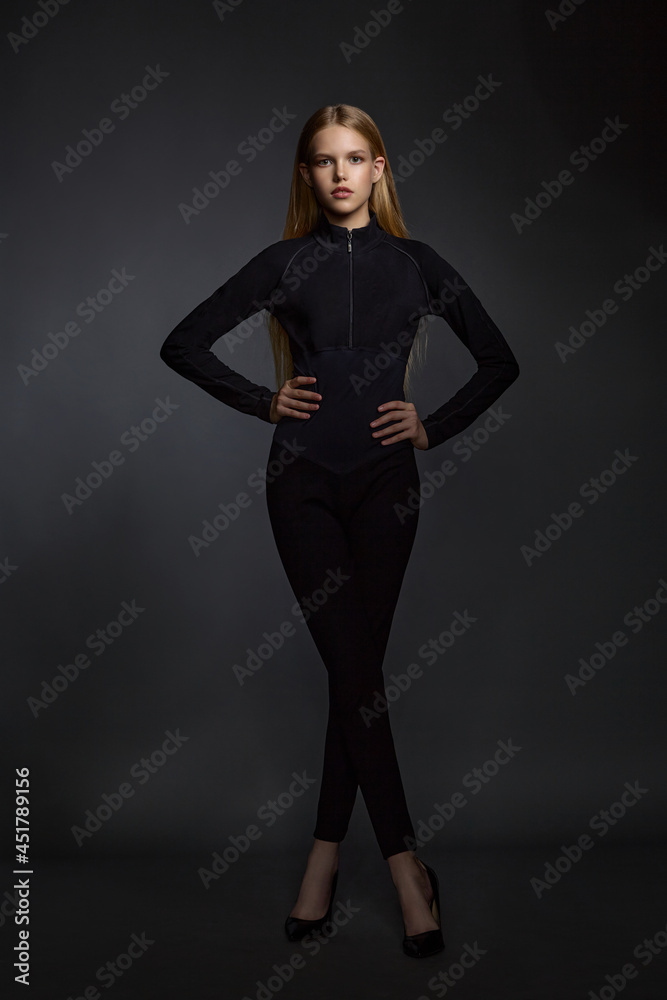 beautiful girl blonde teenager in black clothes posing in the studio on a dark background beautiful girl blonde teenager in black clothes posing in the studio on a dark background