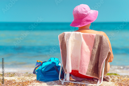 Body positive older woman sitting in chair on the beach