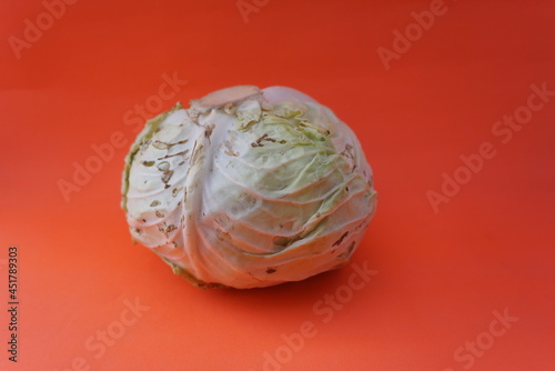 Unspoiled green cabbage on an orange background. Fresh vegetables. Space for text. Copy space. Suitable for vegetables, health care, nutritious food, healthy lifestyle.