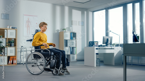 Hospital Physical Therapy: Determined Young Man with Leg Injury is Sitting on a Wheelchair. Miracle of Rehabilitation, Strong Mindedness, Willpower, Professional Doctors.