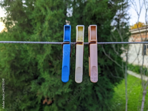 colored plastic clothespins hanging on a rope in the yard against a blurred background.