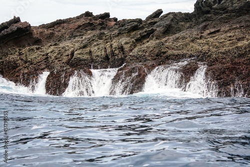 Scenic view of tropical rocky island in sea. Water splash and flowing motion. For environment and geology background. No people.