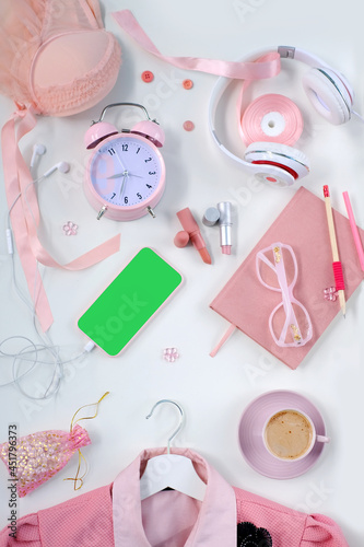 womens stylish accessories, smartphone with blank screen, glamorous set in pink shades, flat lay, copy background, womens clothing, alarm clock, lipstick, coffee cup, good morning concept, female life