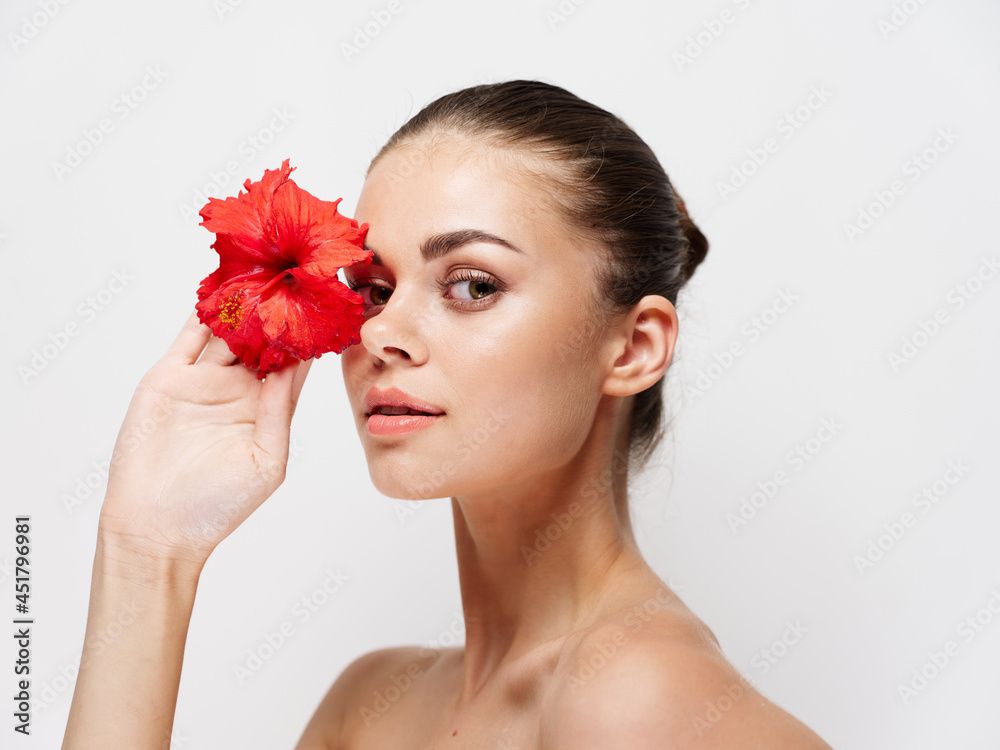 woman with red flower in front of eyes naked shoulders clear skin model woman with red flower in front of eyes naked shoulders clear skin model