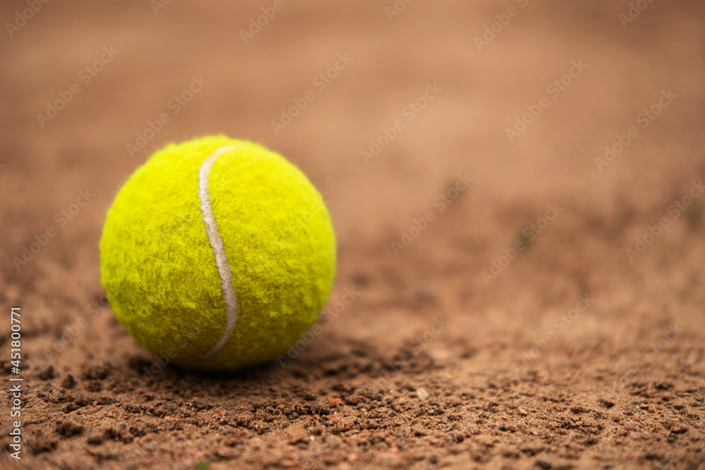 A bright yellow tennis ball is lying on the ground of the court.