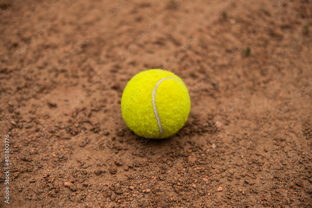 A bright yellow tennis ball is lying on the ground of the court.