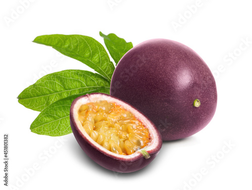 Delicious ripe passion fruits and green leaves on white background