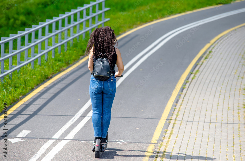  Girl rides an electric scooter in the summer Park
