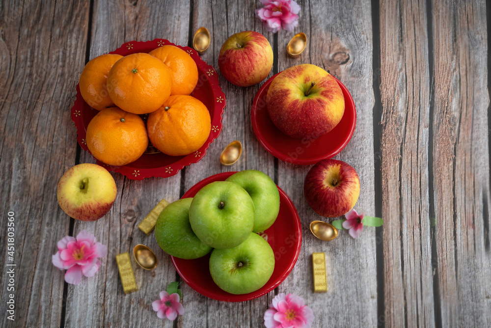 Tangerine Orange ,red apple , green apple in red plate ,accessories on lunar new year & chinese new year vocation concept and flower on wooden background.